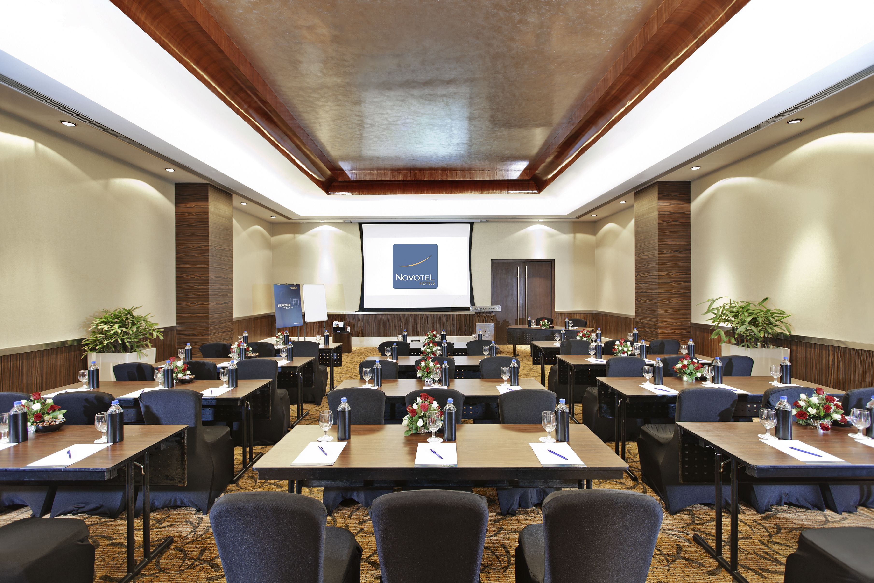 A conference room with multiple tables, chairs, and a presentation screen.