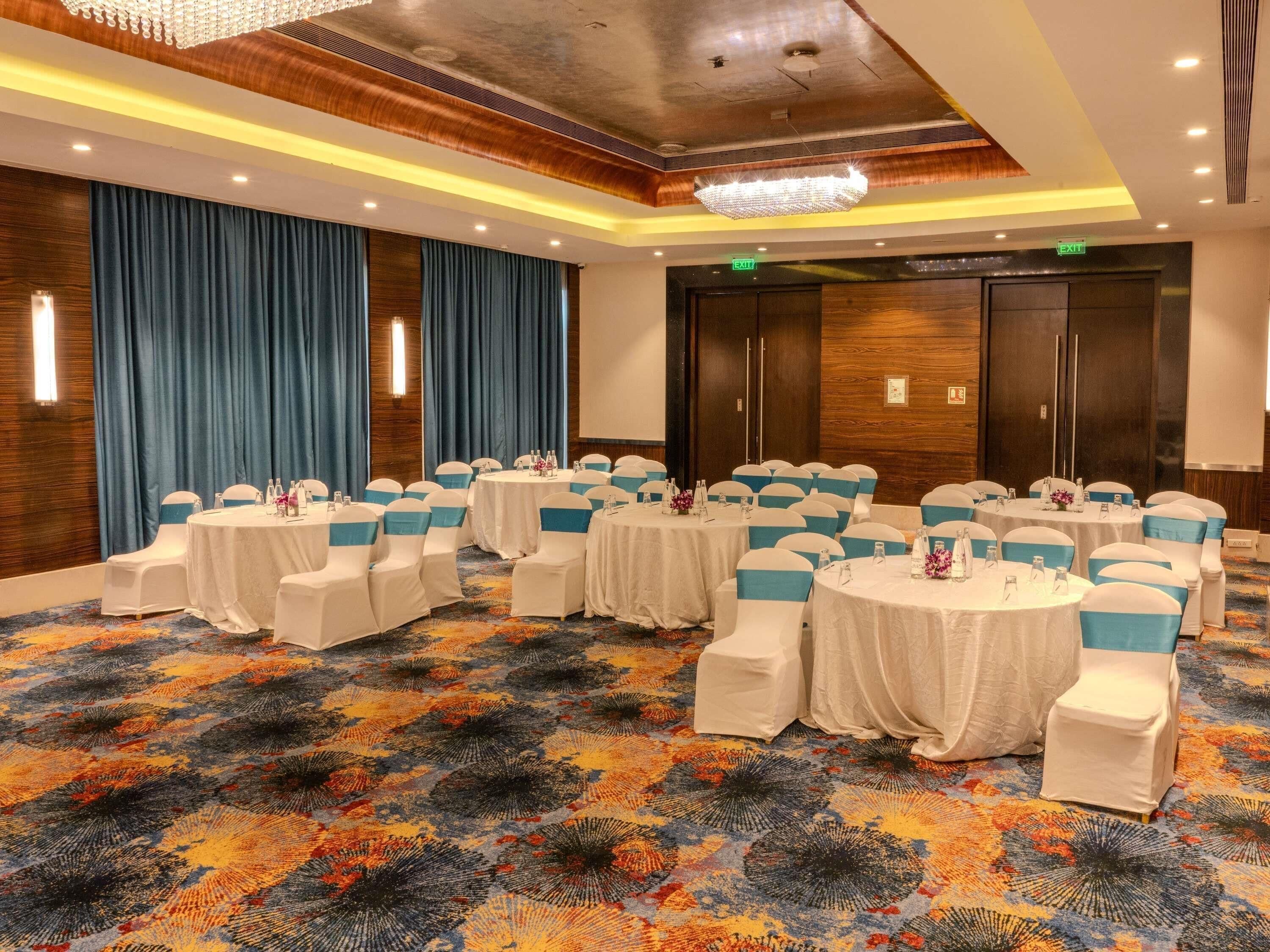 A conference room with round tables, white chairs, and blue sashes.