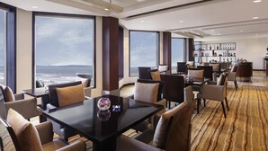 Un hall d’hôtel moderne doté d’un grand espace salon, d’un bar et offrant une vue sur l’océan.