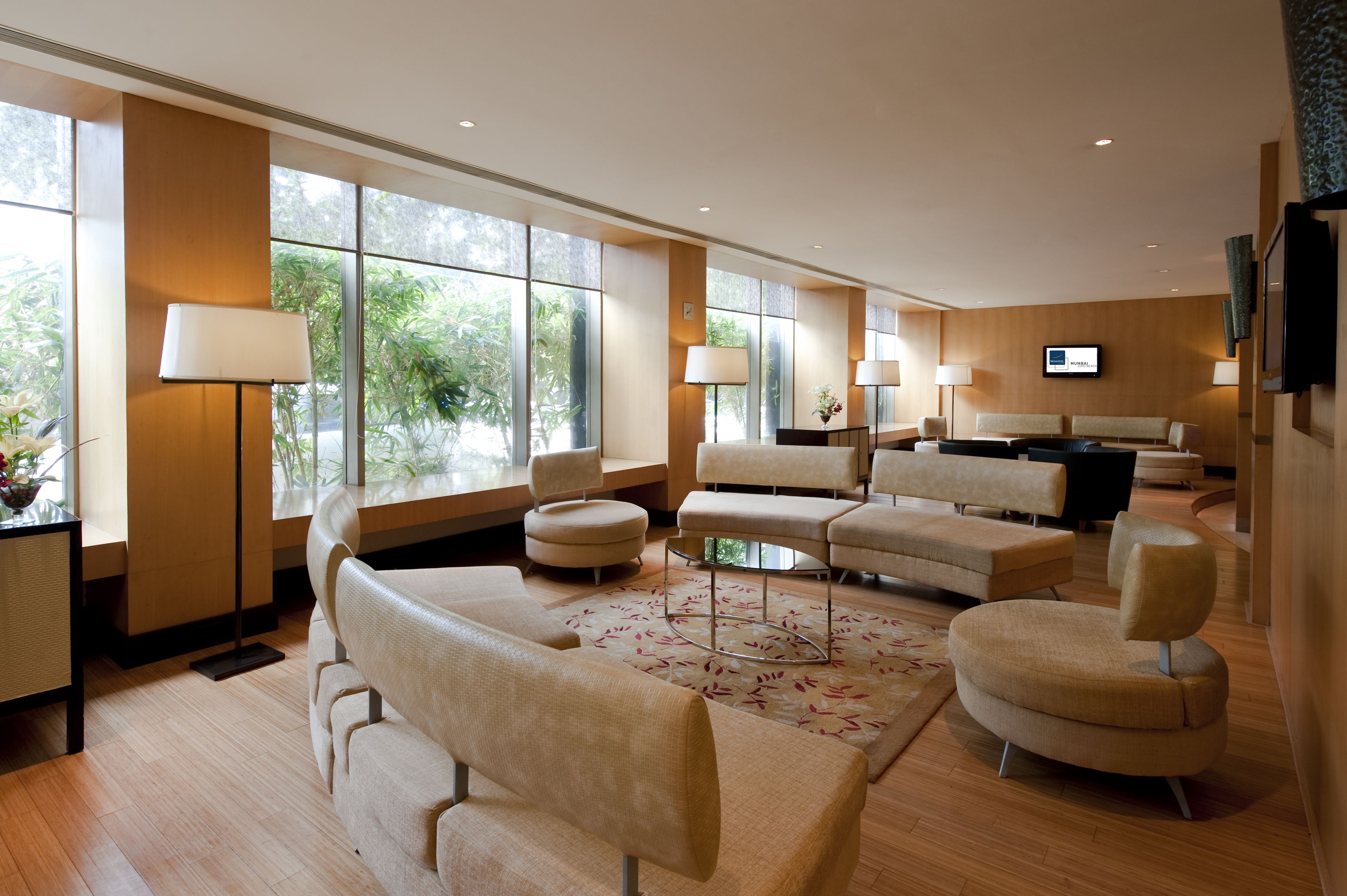 Een moderne hotel lobby met een zithoek, grote ramen en een flatscreen televisie.