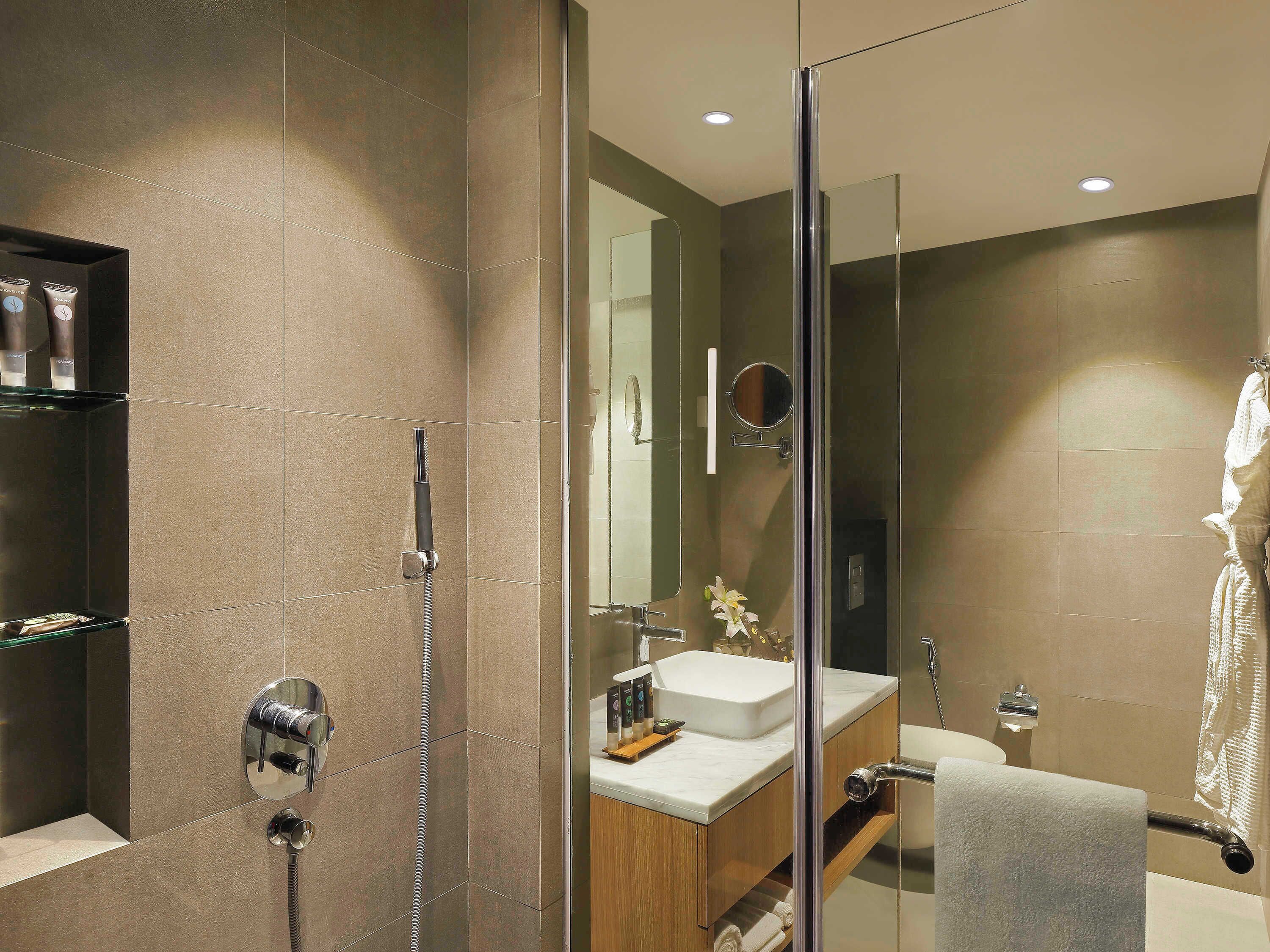 A modern bathroom with a glass-enclosed shower, a vanity with a sink, and a mirror.