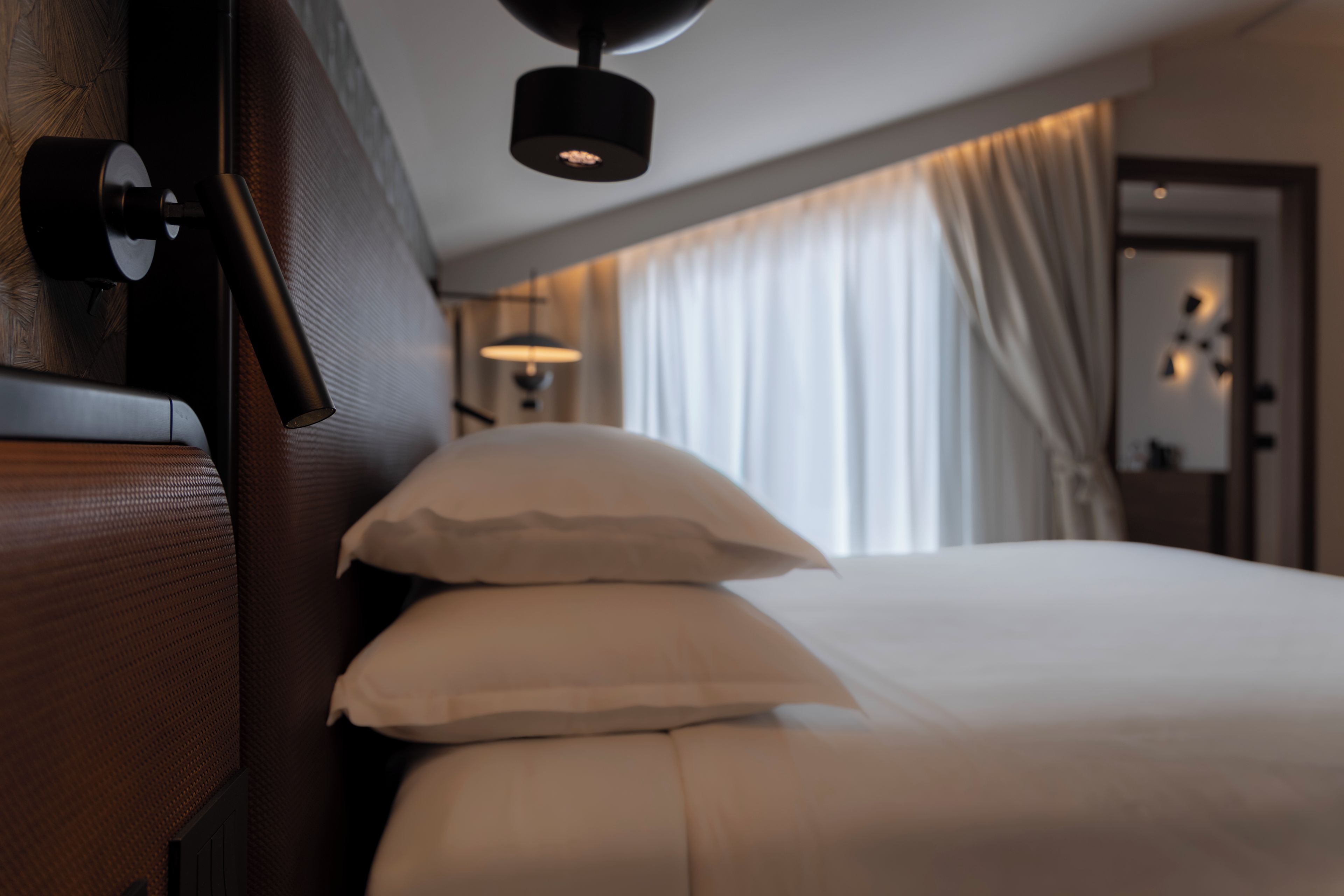 Habitació d'hotel amb un llit, una taula de nit i una làmpada.