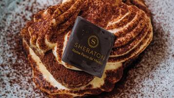 Uma sobremesa em um prato de cerâmica com um pedaço de chocolate com a inscrição 'Sheraton Rome Parco de' Medici'.