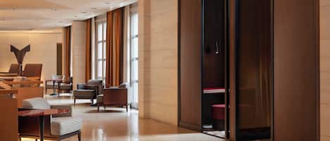 En modern hotellobby med en lång korridor, en sittgrupp och ett stort fönster.