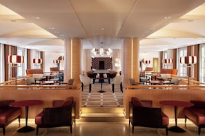 A hotel lobby with a central seating area, multiple tables, and chairs. - Sheraton Rome Parco de’ Medici (Rome)
