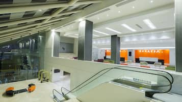 A modern interior with an escalator, glass railings, and a seating area with orange accents.