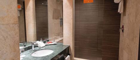 A modern bathroom with a marble sink, a glass shower enclosure, and a towel rack.