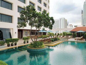 Relax by the pool surrounded by lush greenery and comfortable seating.