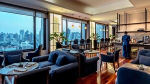 A modern hotel room with a city view, a dining area, and a kitchen. - Grand Mercure Bangkok Atrium (Bangkok)