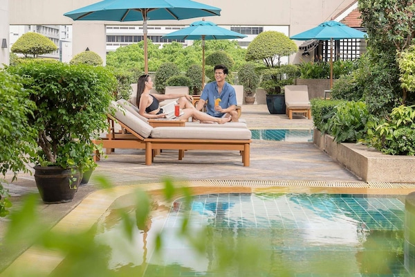 Una piscina al aire libre, sombrillas, sillones reclinables de piscina