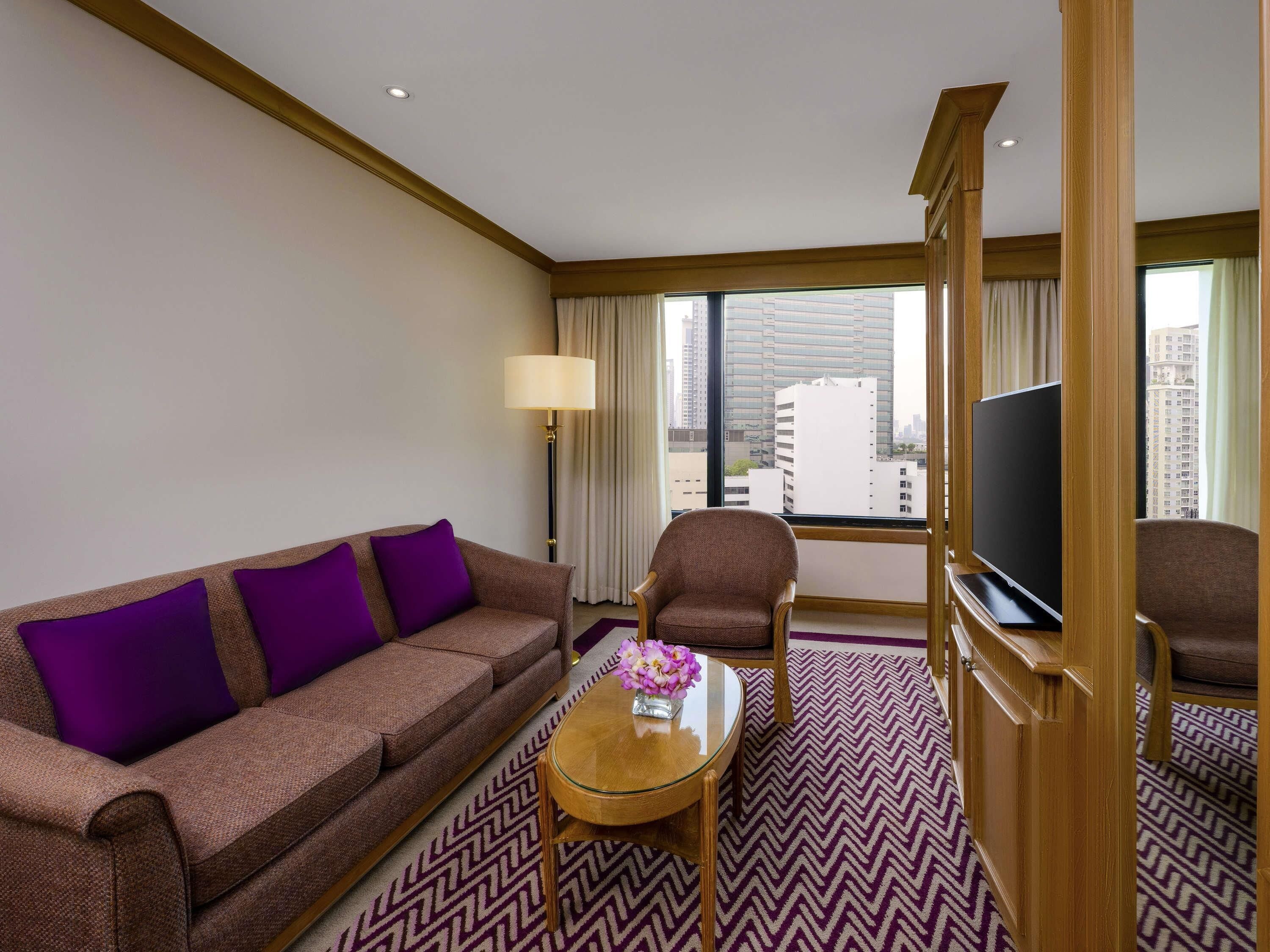 Una habitación de hotel con sofá, sillón y televisor.