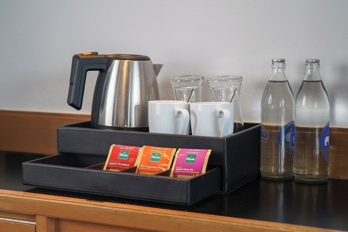 A coffee station with a coffee maker, cups, and bottled water.