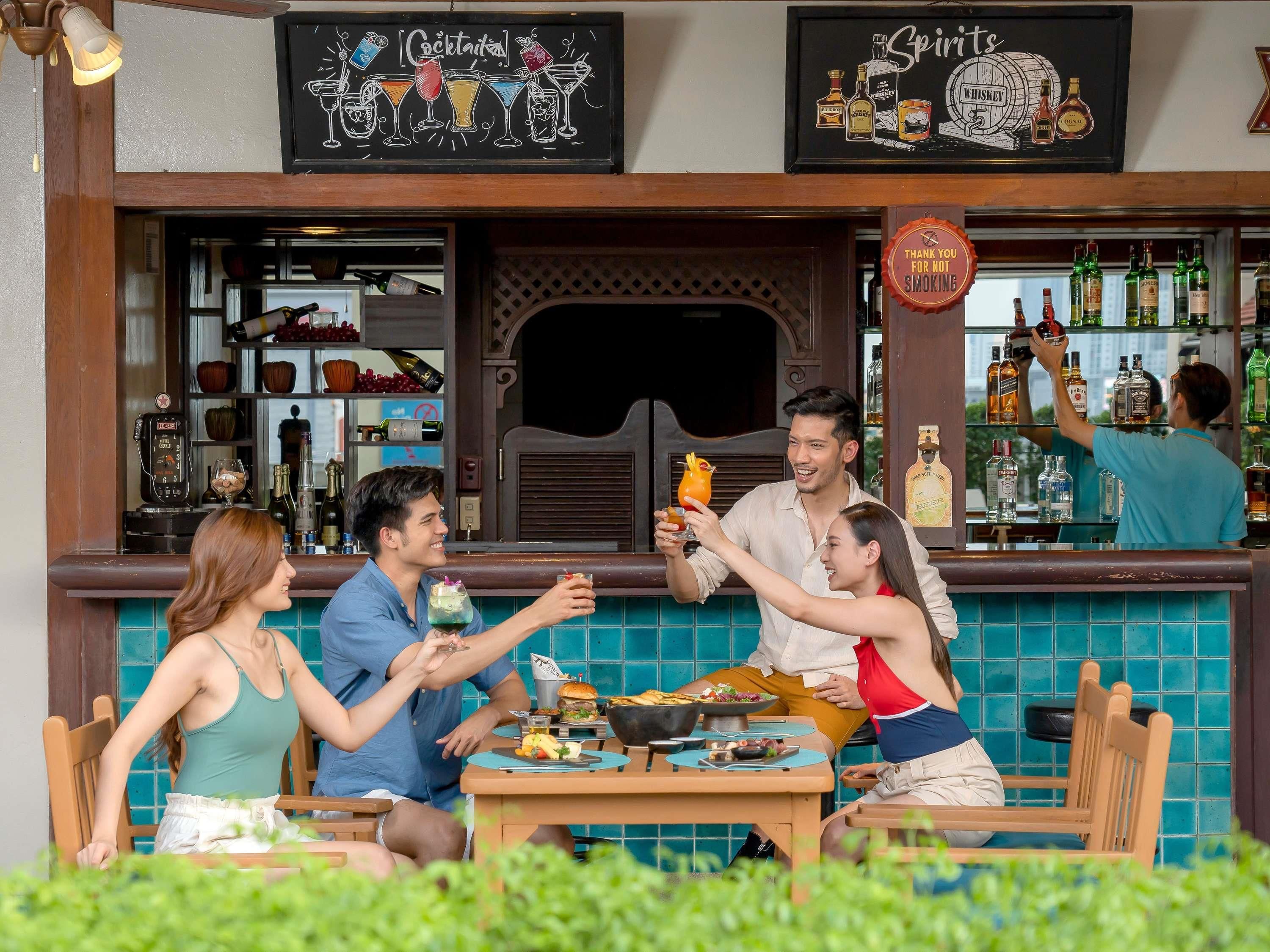 A bar area with a signboard, a counter with bottles, and a dining table with food.