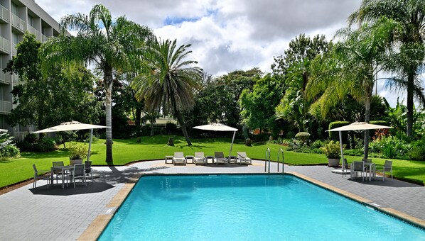 Una piscina al aire libre, sombrillas, tumbonas