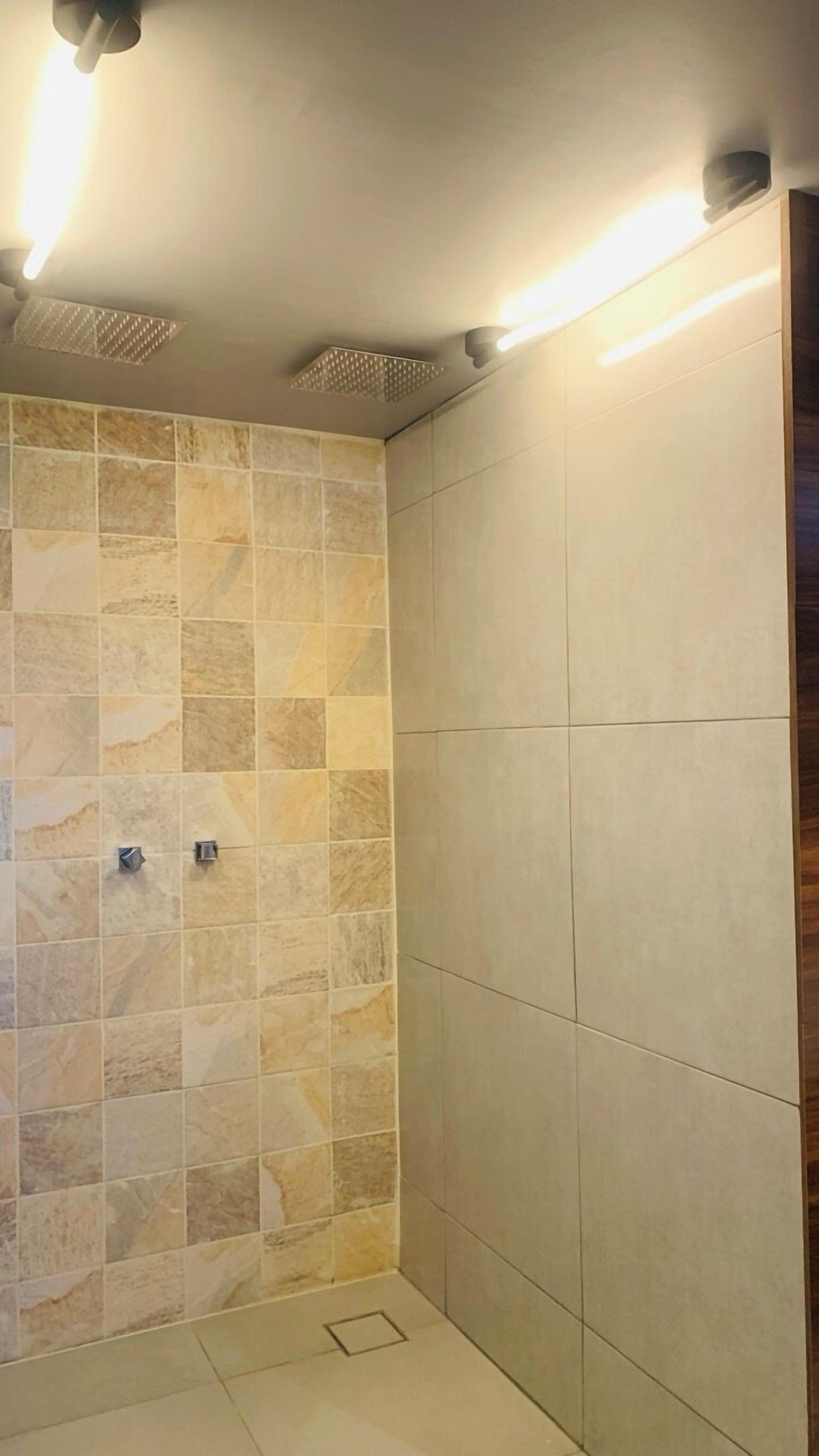 A shower area with tiled walls and a tiled floor.