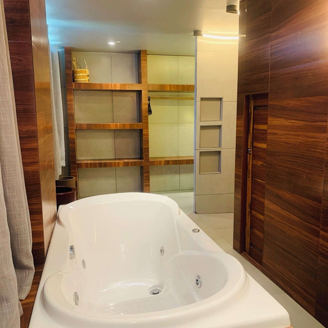 Un baño moderno con una bañera independiente, paneles de madera y estantes empotrados.