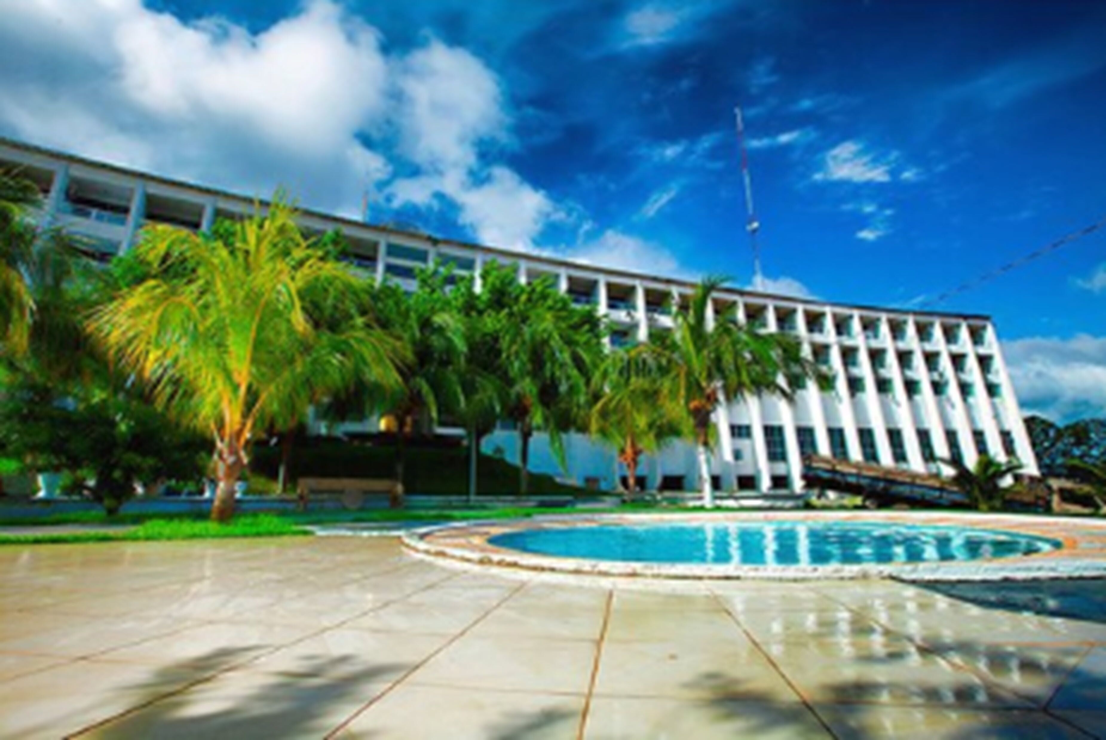 Un edificio moderno con piscina y palmeras al frente.