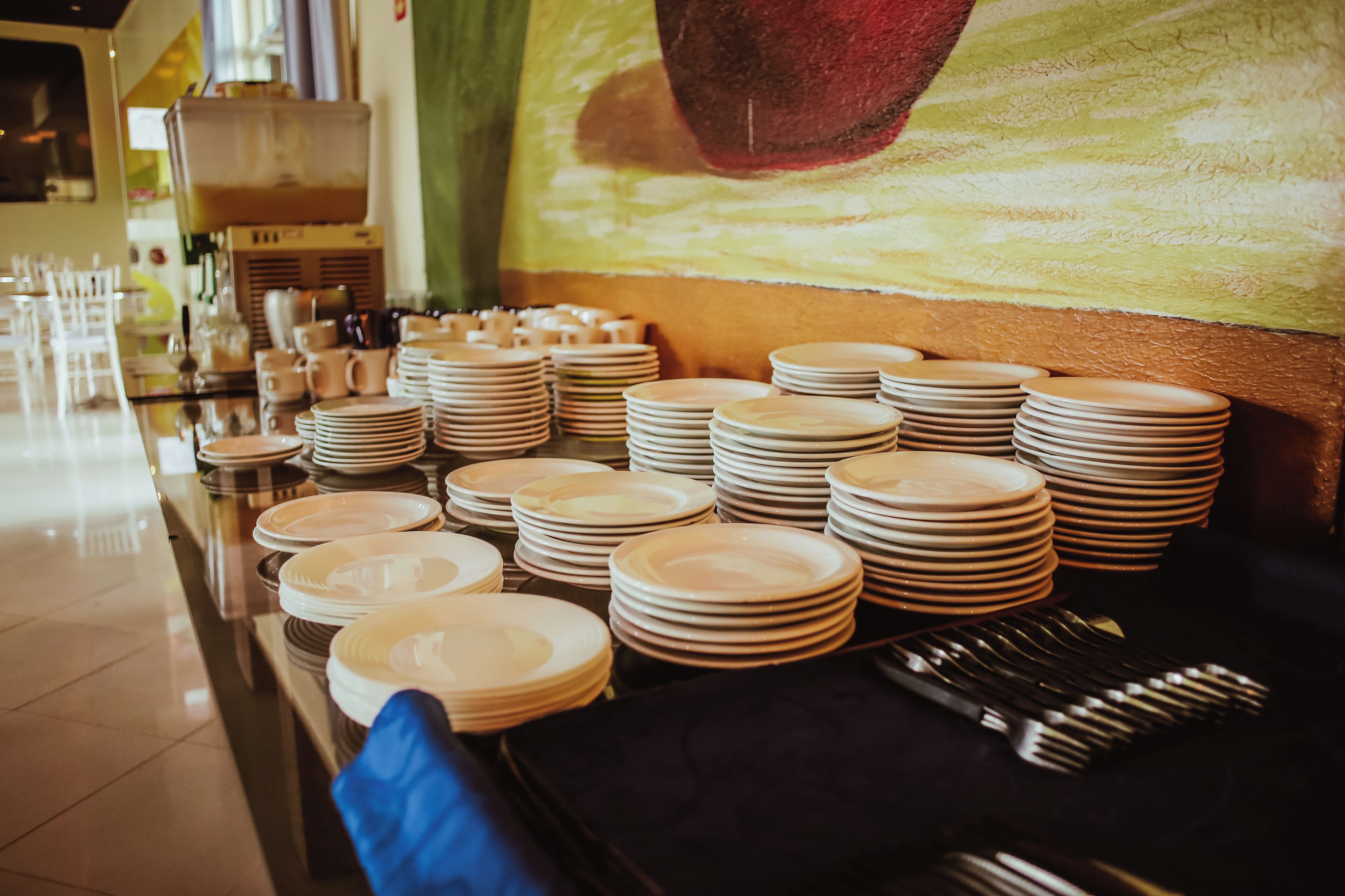 A buffet setup with multiple stacks of plates and cutlery.