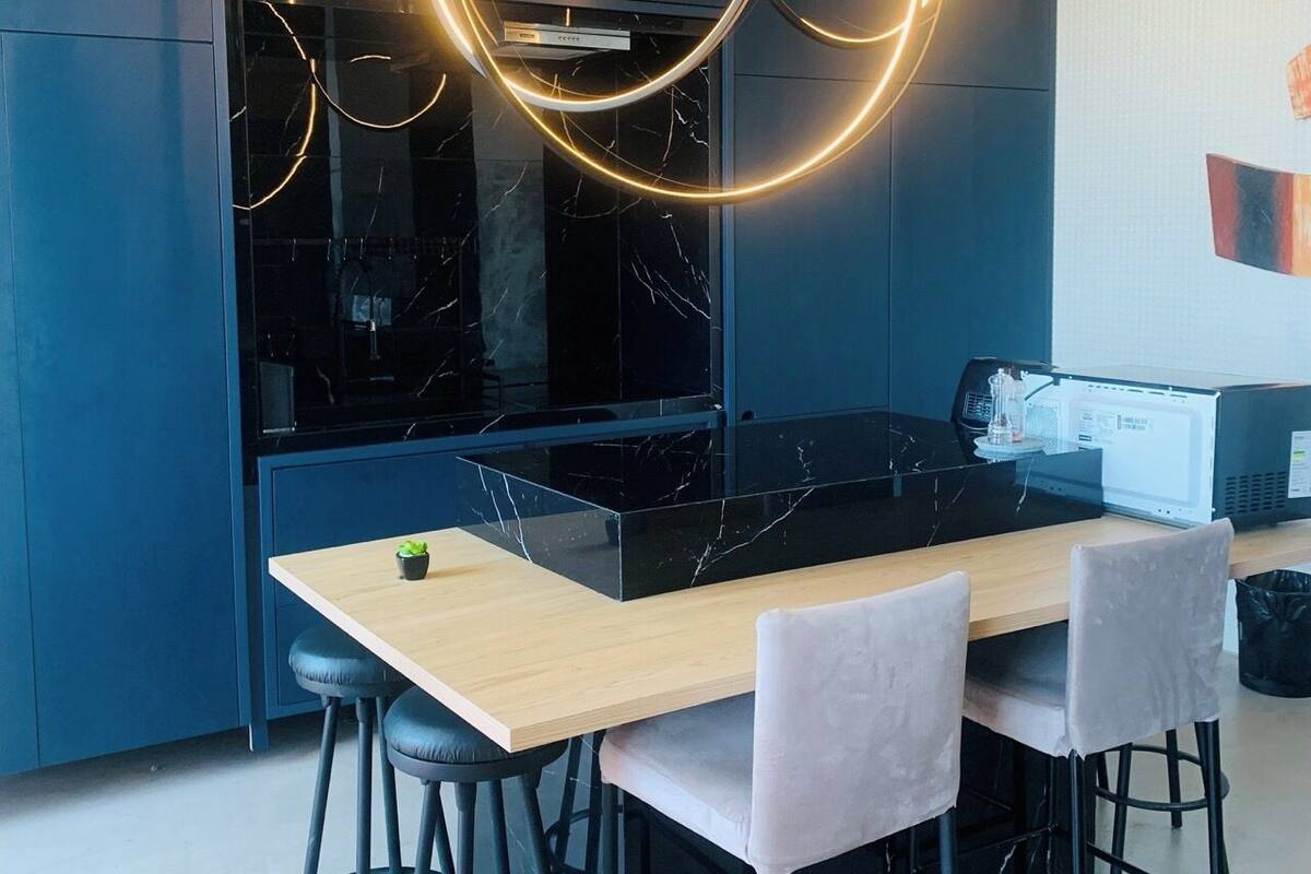 A modern kitchen with a marble countertop, black cabinets, and a wooden dining table with four chairs.