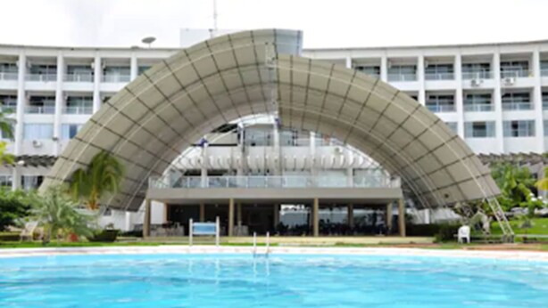 A modern building with a large arched structure over a swimming pool. - Barrudada Tropical Hotel (Santarém)
