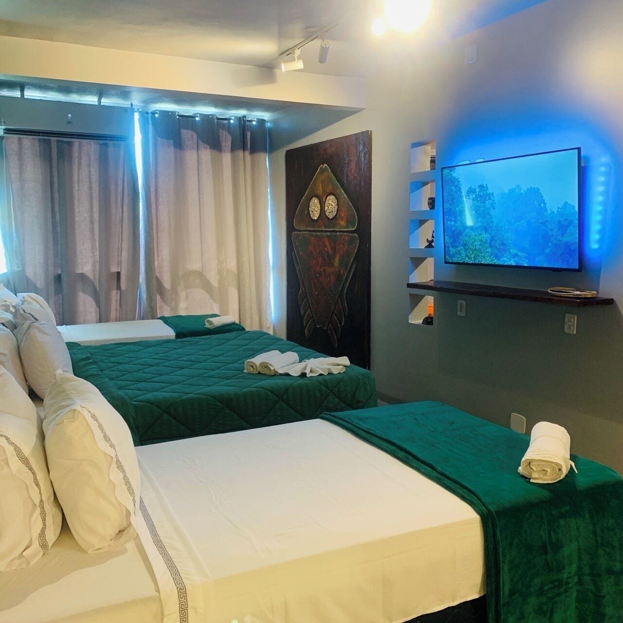 A hotel room with two beds, a television, and a wall-mounted shelf.
