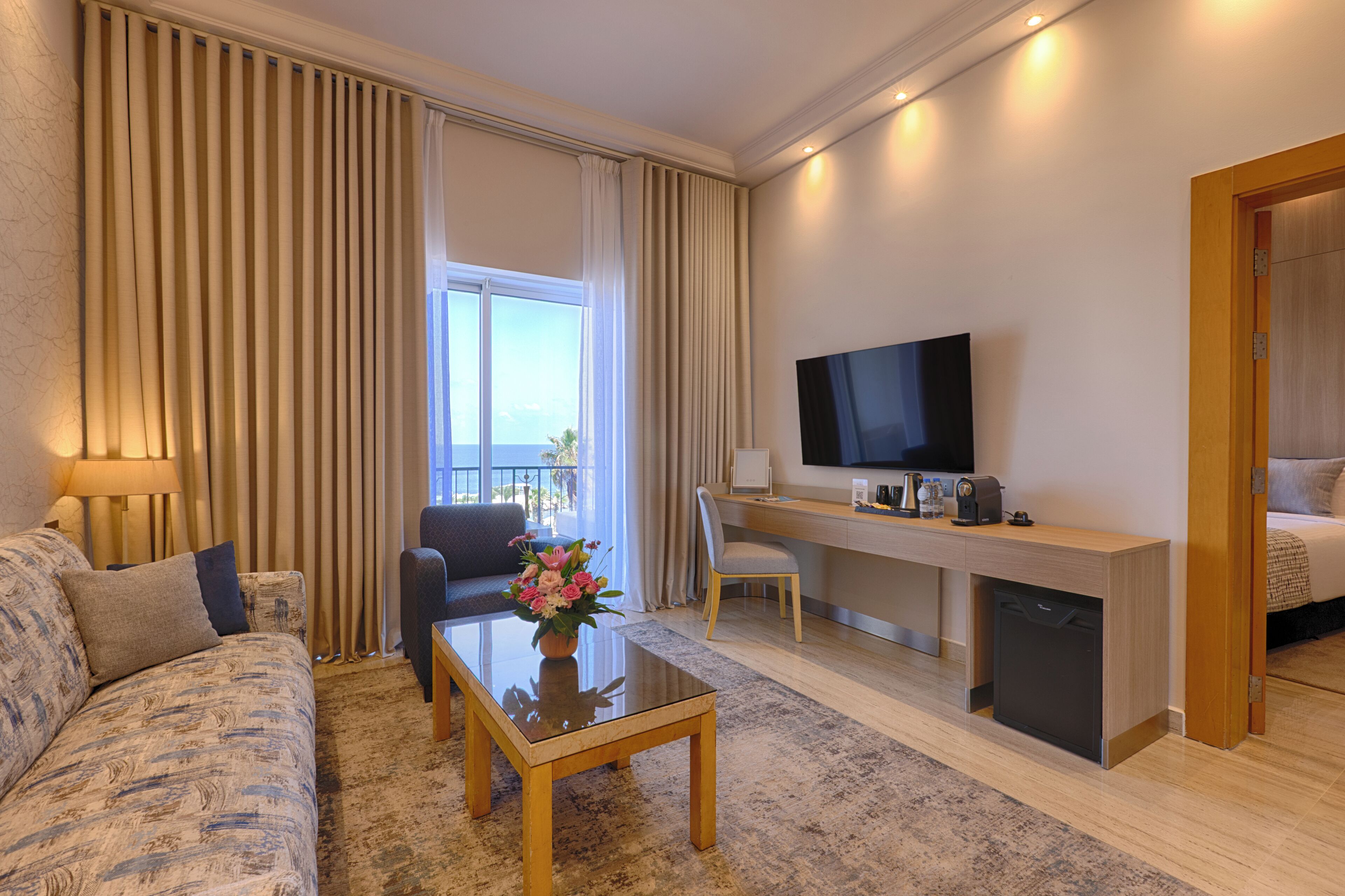Una habitación de hotel con un sofá, un escritorio con una computadora, un televisor y una cama.