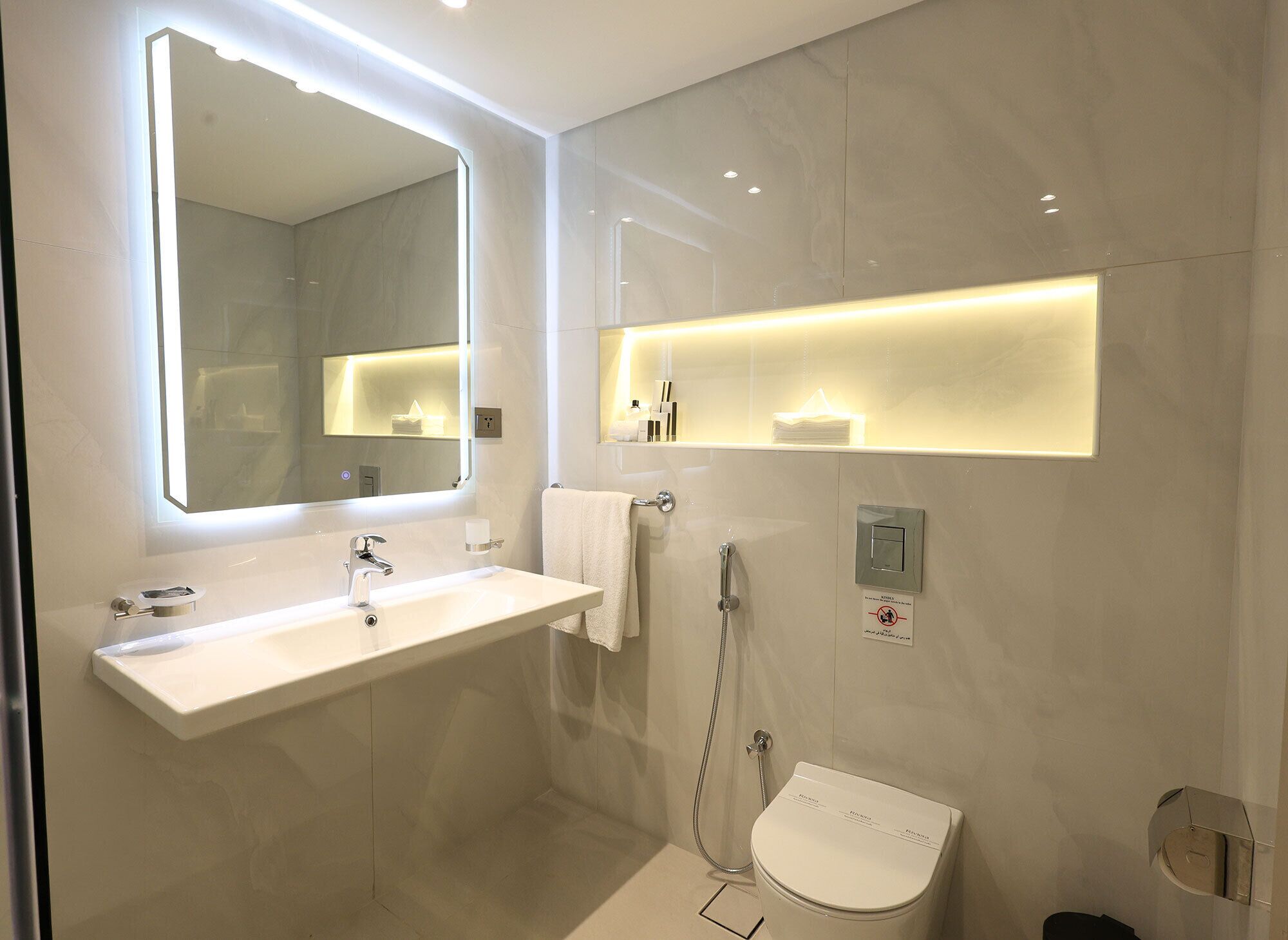 Un baño moderno con un espejo grande, un lavabo, un inodoro y una ducha.