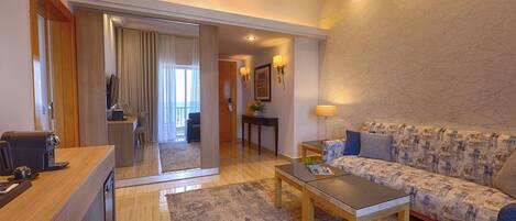 Una habitación de hotel moderna con sofá, una mesa de centro y un escritorio con cafetera.
