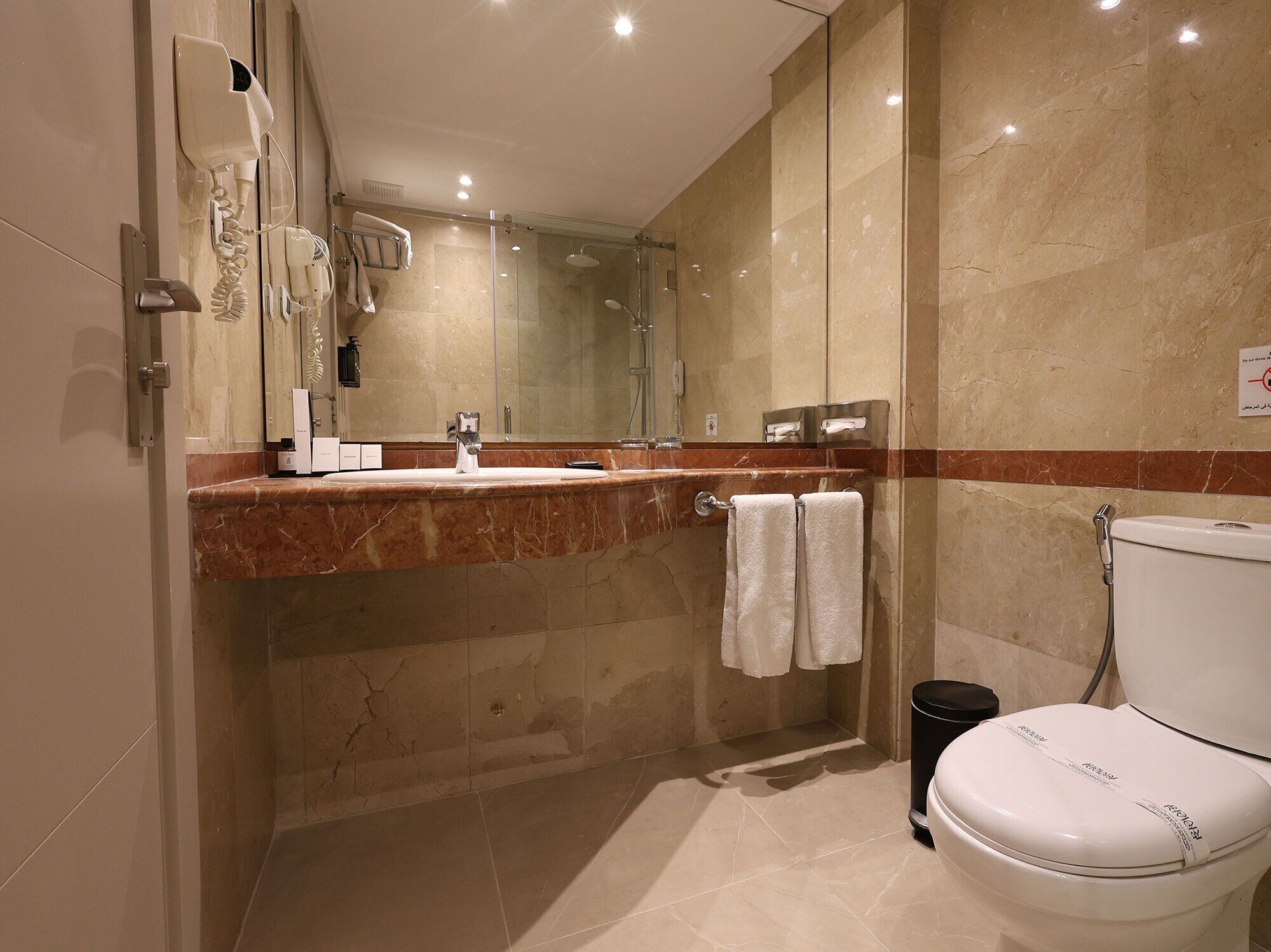 Ein modernes Badezimmer mit Waschtisch aus Marmor, einer Duschkabine und einer Toilette.
