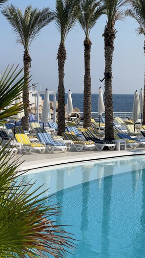A poolside area with lounge chairs and umbrellas, palm trees, and a view of the sea. - Riviera Hotel Beirut (Beirut)