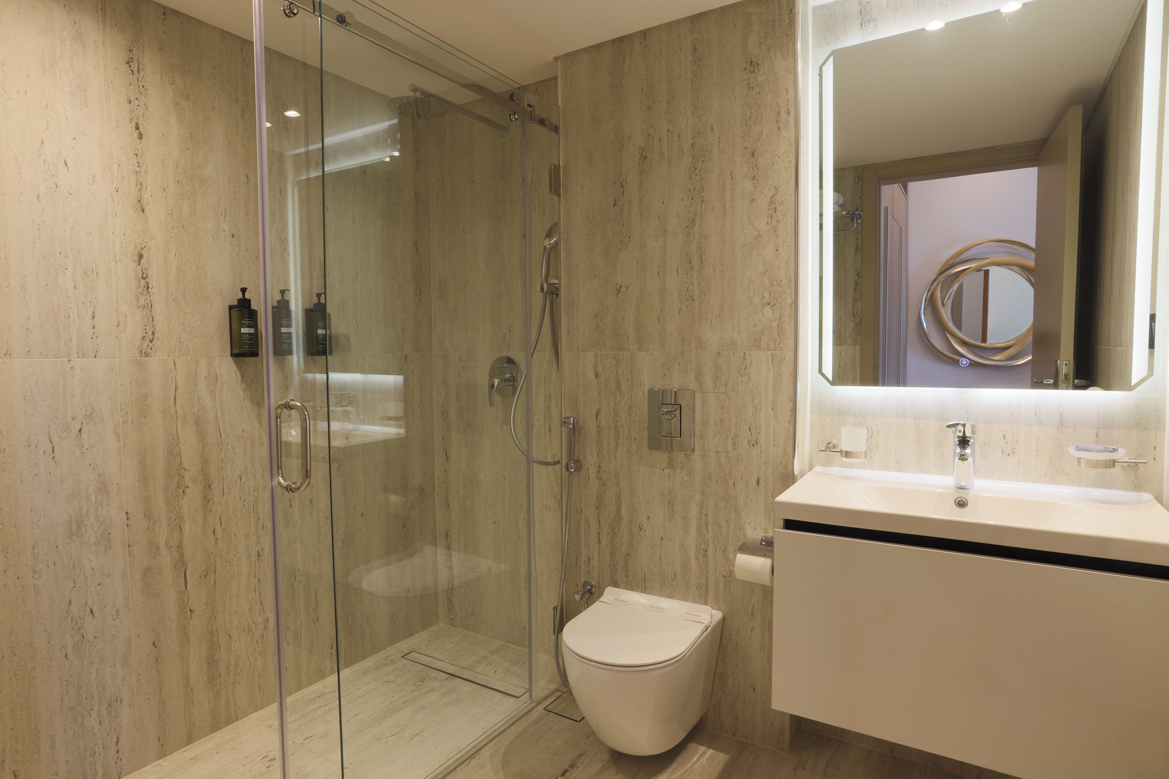 A modern bathroom with a glass-enclosed shower, a white toilet, and a vanity with a mirror.