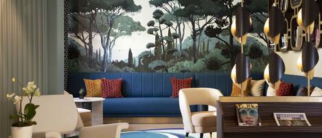 Una sala de estar moderna con un sofá azul, sillas blancas, una mesa de centro y una planta decorativa.