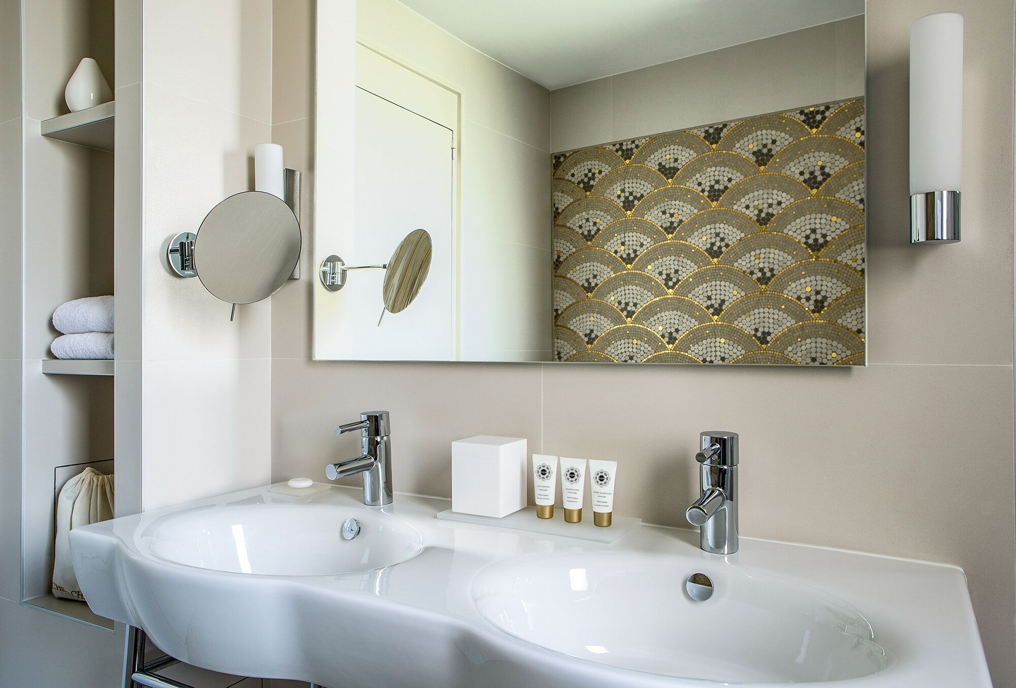 Un baño con dos lavamanos, un espejo grande y un diseño decorativo en la pared.