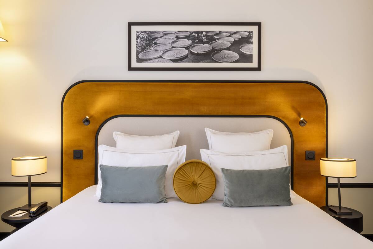 A neatly made bed with a wooden headboard, two bedside lamps, and a framed picture above.