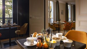 A breakfast setting with a table set for two, including croissants, fruit, and coffee. - Hotel Aiglon (Paris)