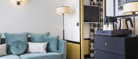 A modern living room with a teal sofa, a black cabinet, and a floor lamp.