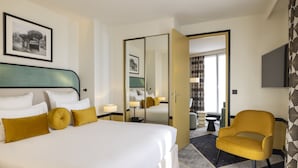 A hotel room with a large bed, a chair, a desk, and a mirror. - Hotel Aiglon (Paris)