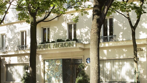 A building with a large, ornate entrance door and a balcony with a metal railing. - Hotel Aiglon (Paris)