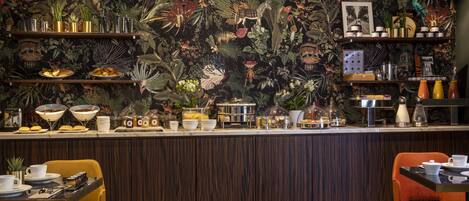 A restaurant with a tropical-themed wall, wooden bar counter, and yellow and orange chairs.
