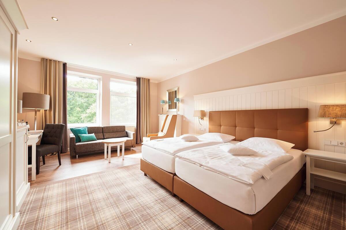 Een hotelkamer met een groot bed, een bank, een bureau en een raam met gordijnen.