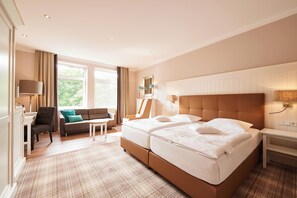 Ein Hotelzimmer mit einem großen Bett, einer Couch, einem Schreibtisch und einem Fenster mit Vorhängen.