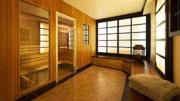 A room with wooden paneling, a large window with multiple panes, a bench, and a small table with a basket.