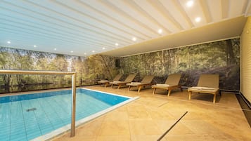 Relax by the serene pool surrounded by lounge chairs and a nature-inspired mural.
