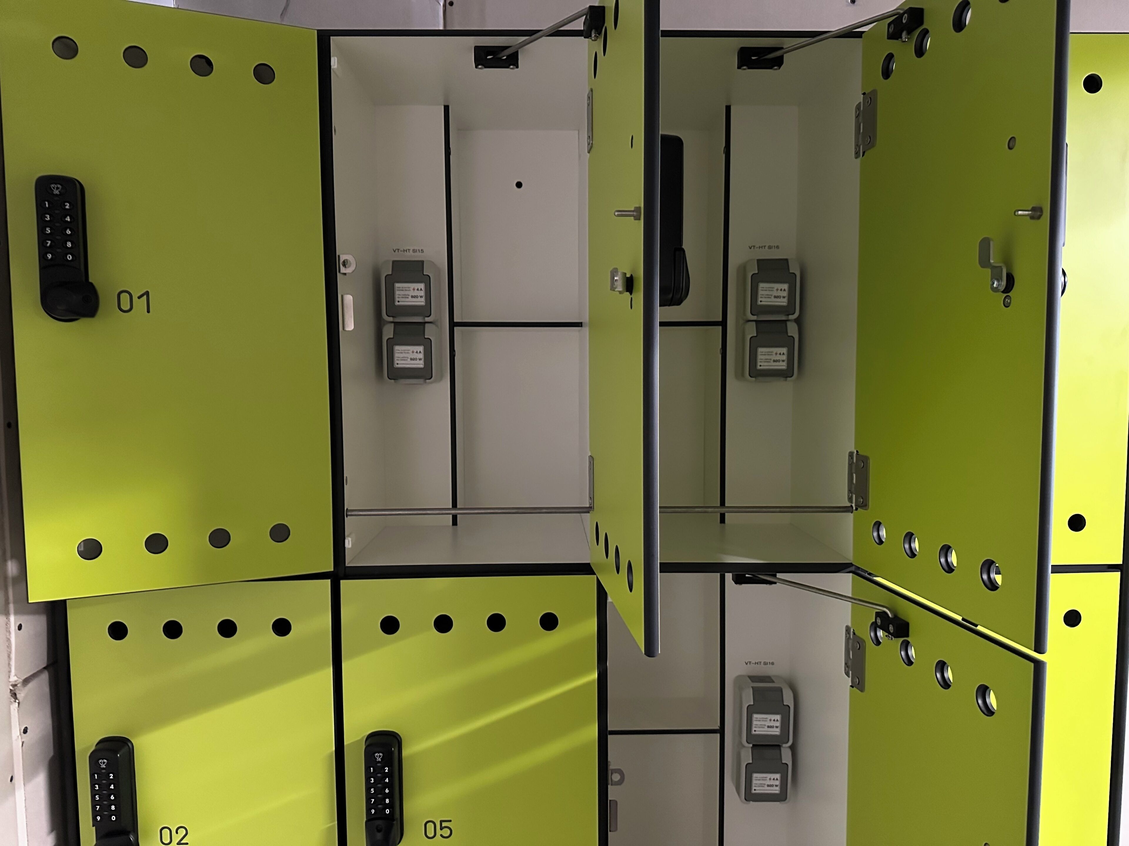 A hotel room with a green color scheme, multiple electrical outlets, and a door with a handle.