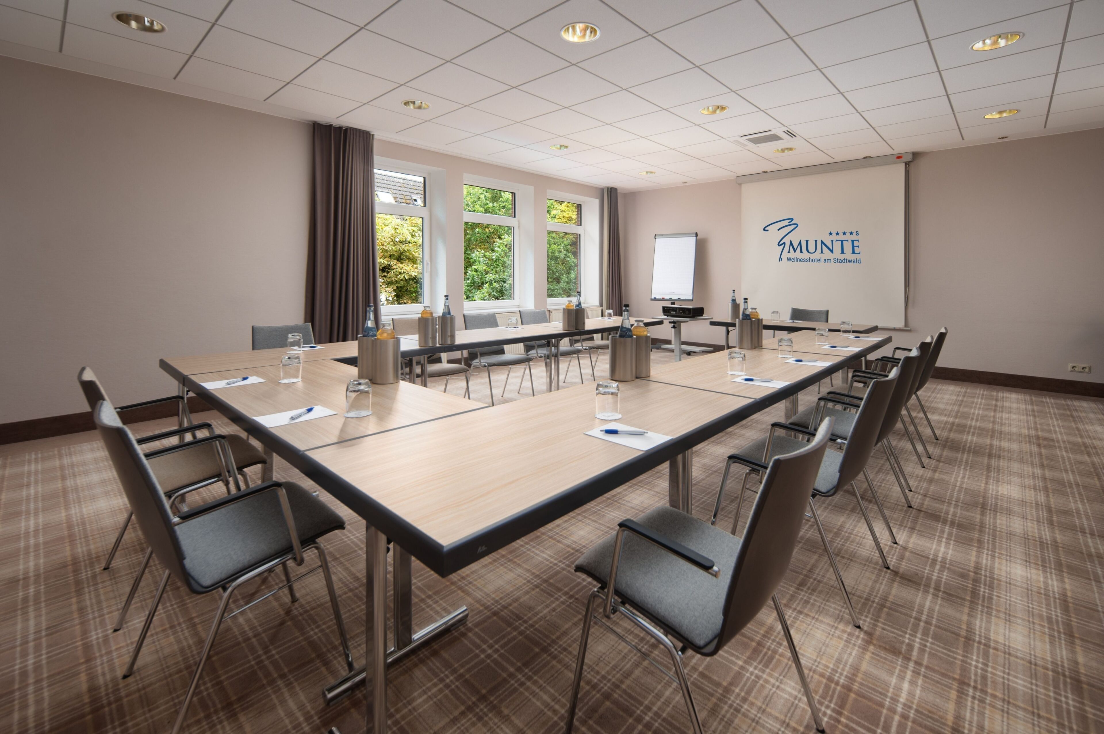 Ein Konferenzraum mit einem langen Tisch, Stühlen, einer Projektionsleinwand und einer Präsentationsleinwand.