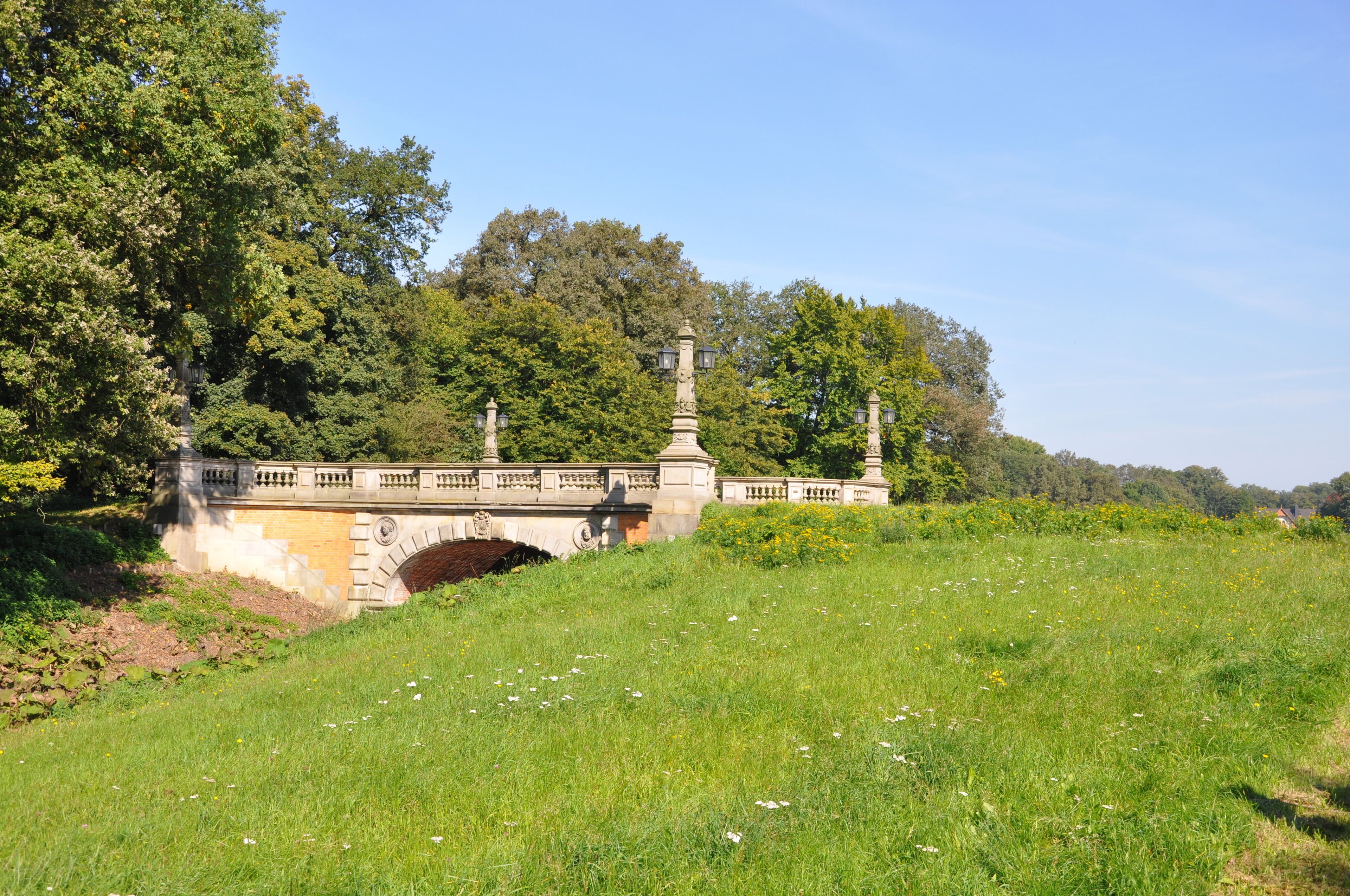 Eine Steinkonstruktion mit aufwendiger Balustrade, umgeben von üppiger Vegetation und Bäumen.