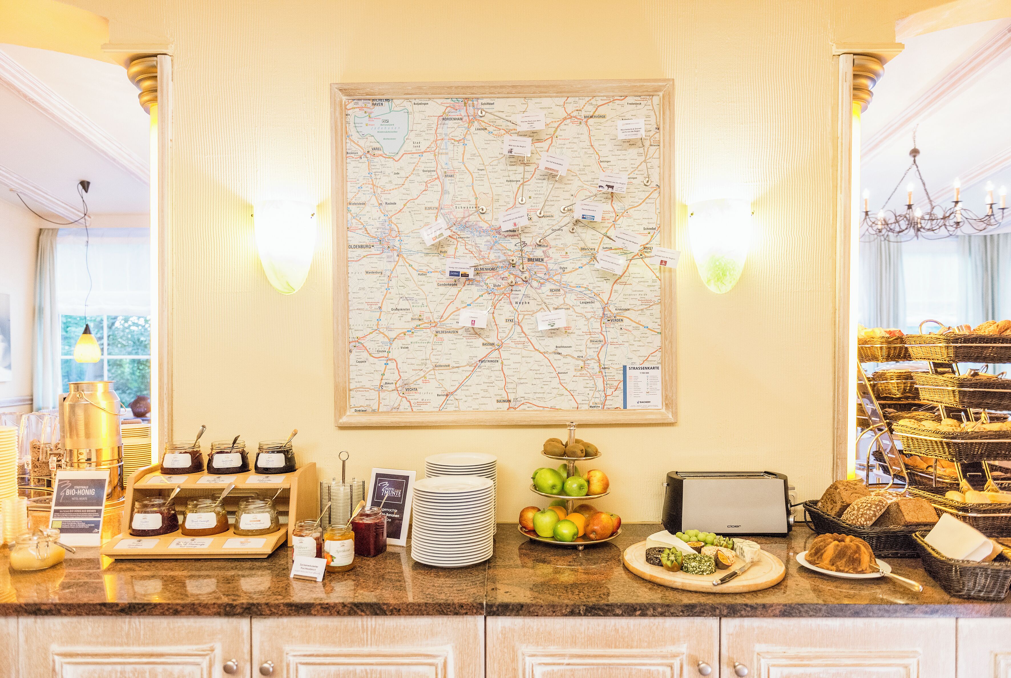 Zona de recepción de un hotel con un gran mapa, una exhibición de frutas y diversas opciones de comida.