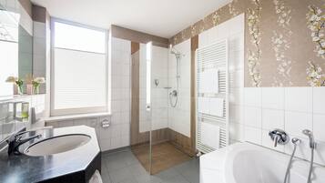 Un baño moderno con ducha de vidrio, lavamanos grande y bañera.