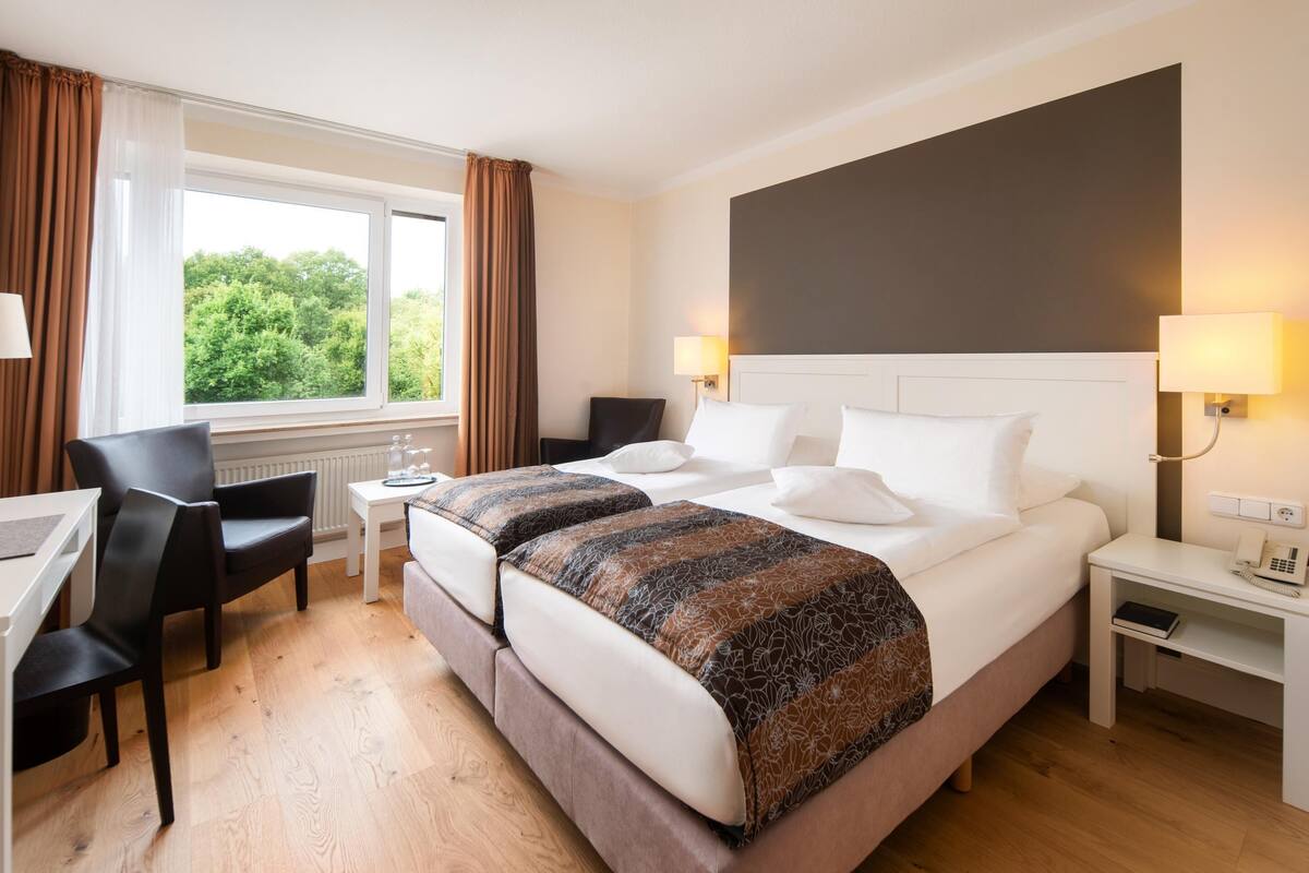 Een hotelkamer met twee bedden, een bureau en een stoel.