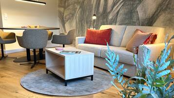 Una sala de estar moderna con sofá, sillas, una mesa de centro y un comedor con sillas y una mesa.